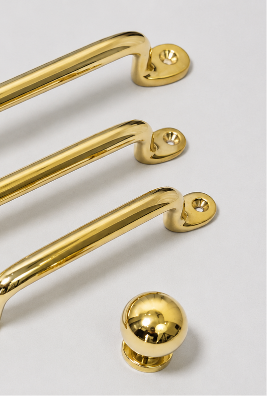 Three polished gold metal cabinet handles of varying widths and a matching round gold knob, displayed on a clean light gray background.